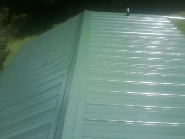 New green metal panels meeting at the ridge of a roof — Flat Roof Repair work by our crew in Moran