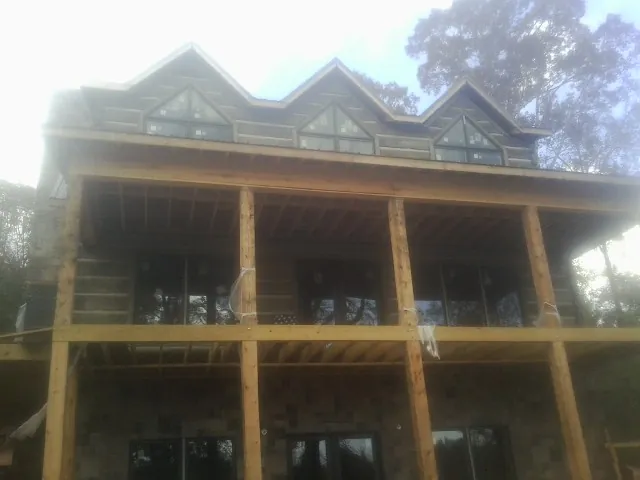 Dormers and porch framing on a large log home under construction — Roof Coating work by our crew in Moran