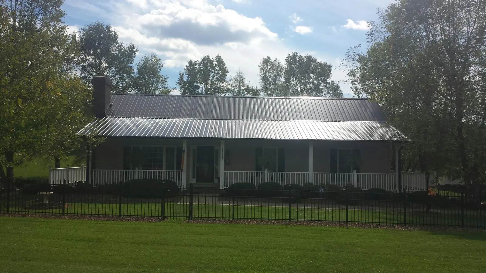 Gray metal roof on a brick ranch with a full width front porch — Gutter Guard Installation work by our crew in Moran
