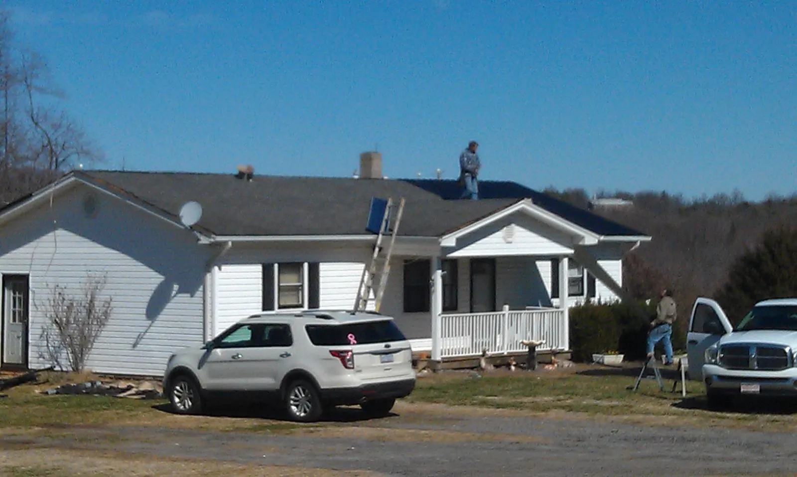 Roofers stripping shingles from a white ranch house roof in Moran