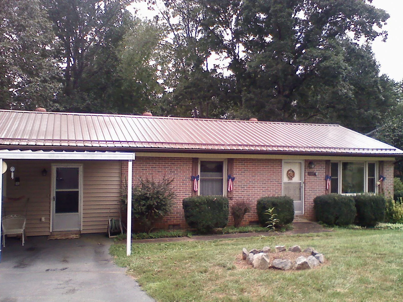 Bronze metal roof and carport on a brick ranch home — Roof Repair work by our crew in Moran