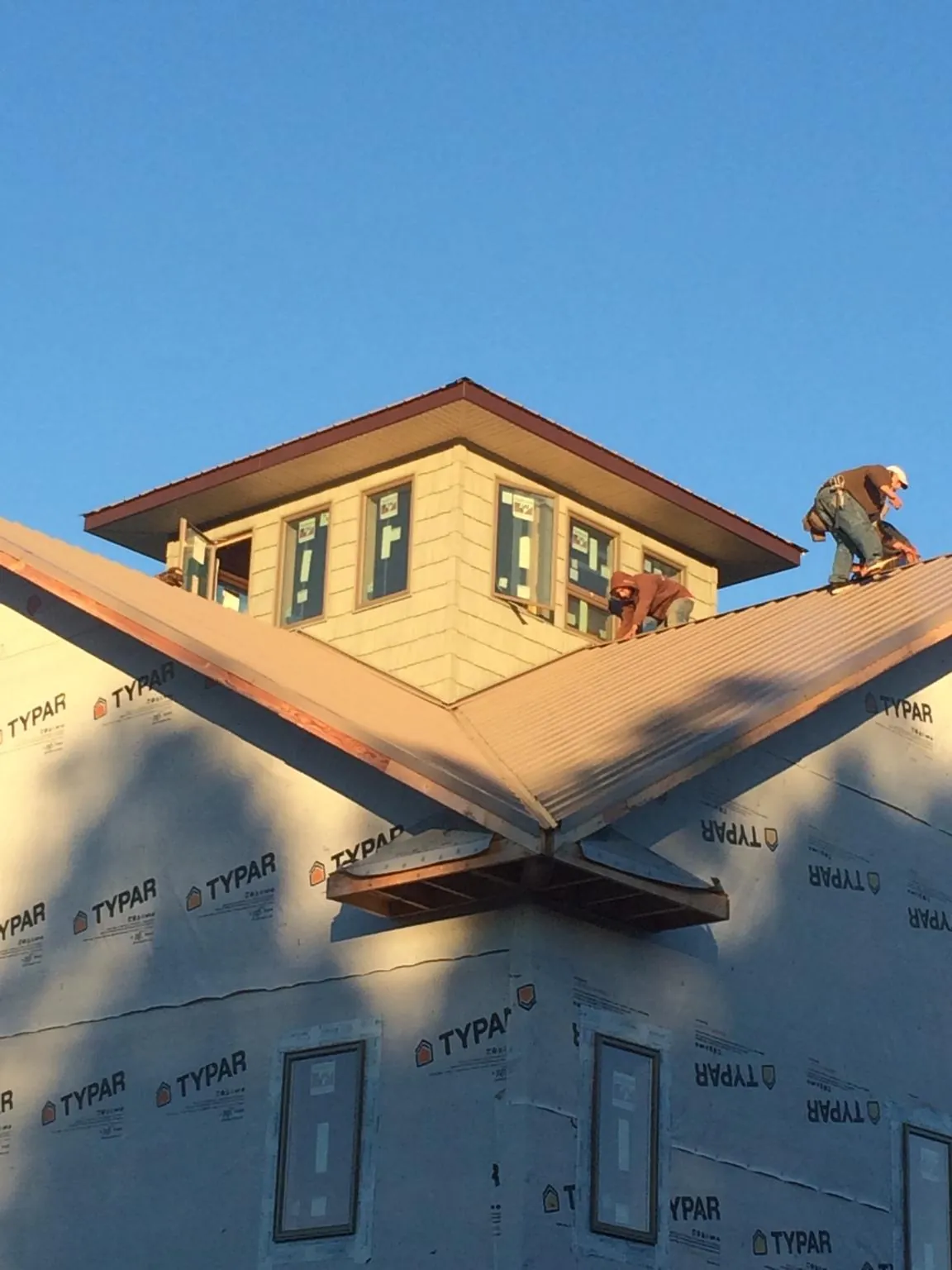 Roofers working around a rooftop cupola on a new metal roof at sunset — Roof Waterproofing in Moran by Roofing Brothers